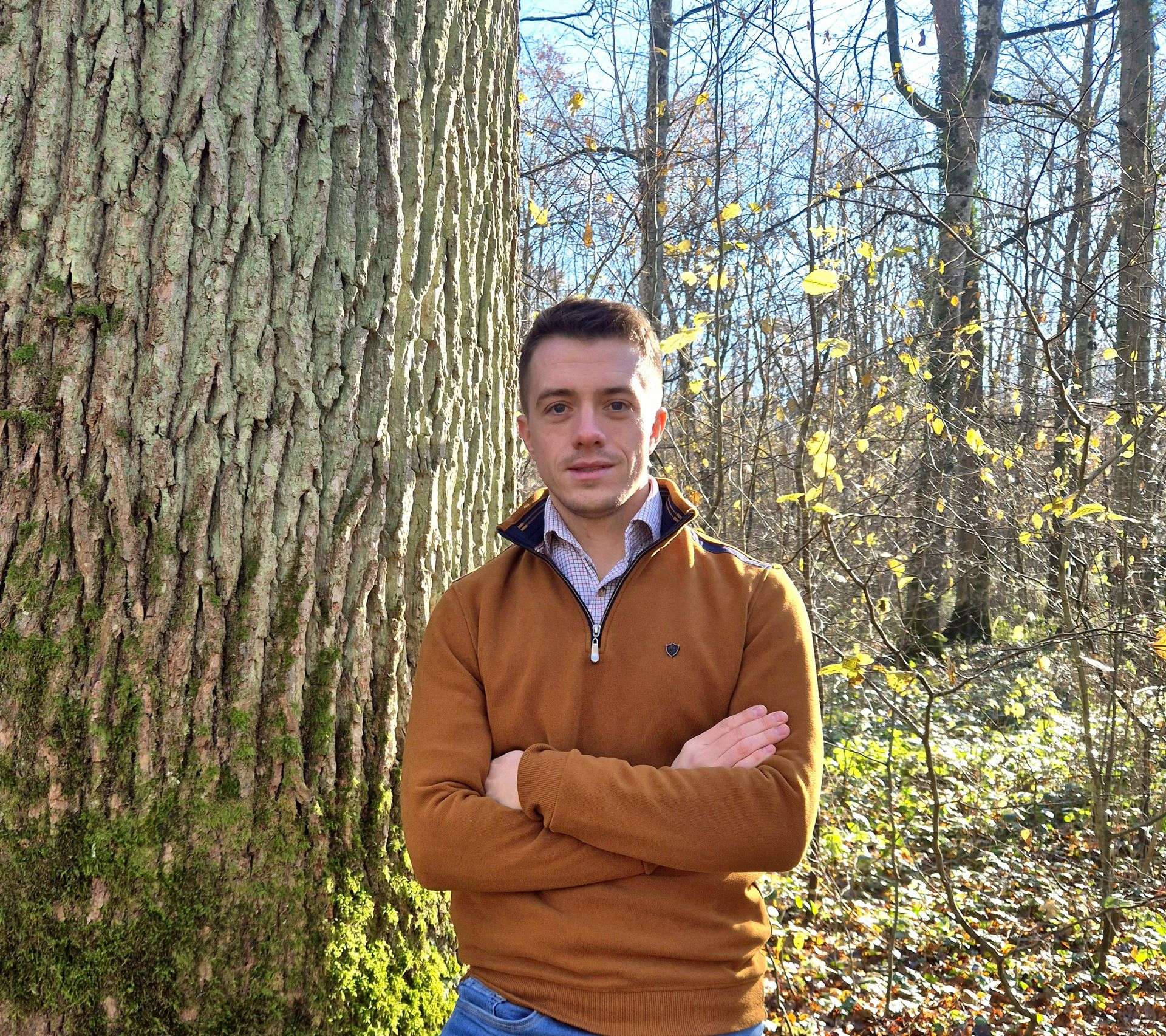 Matthieu Bouclet, fondateur de MB Forêts Transactions, posant devant un grand arbre dans une forêt, reflétant son expertise et son lien profond avec le monde forestier.